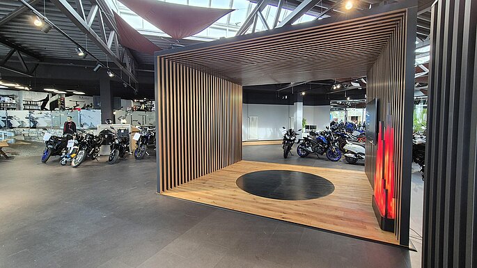 Lamellenbox für Motorradausstellung in schwarz mit TV und künstlicher Feuerstelle Motorshop in Rehau 2026
